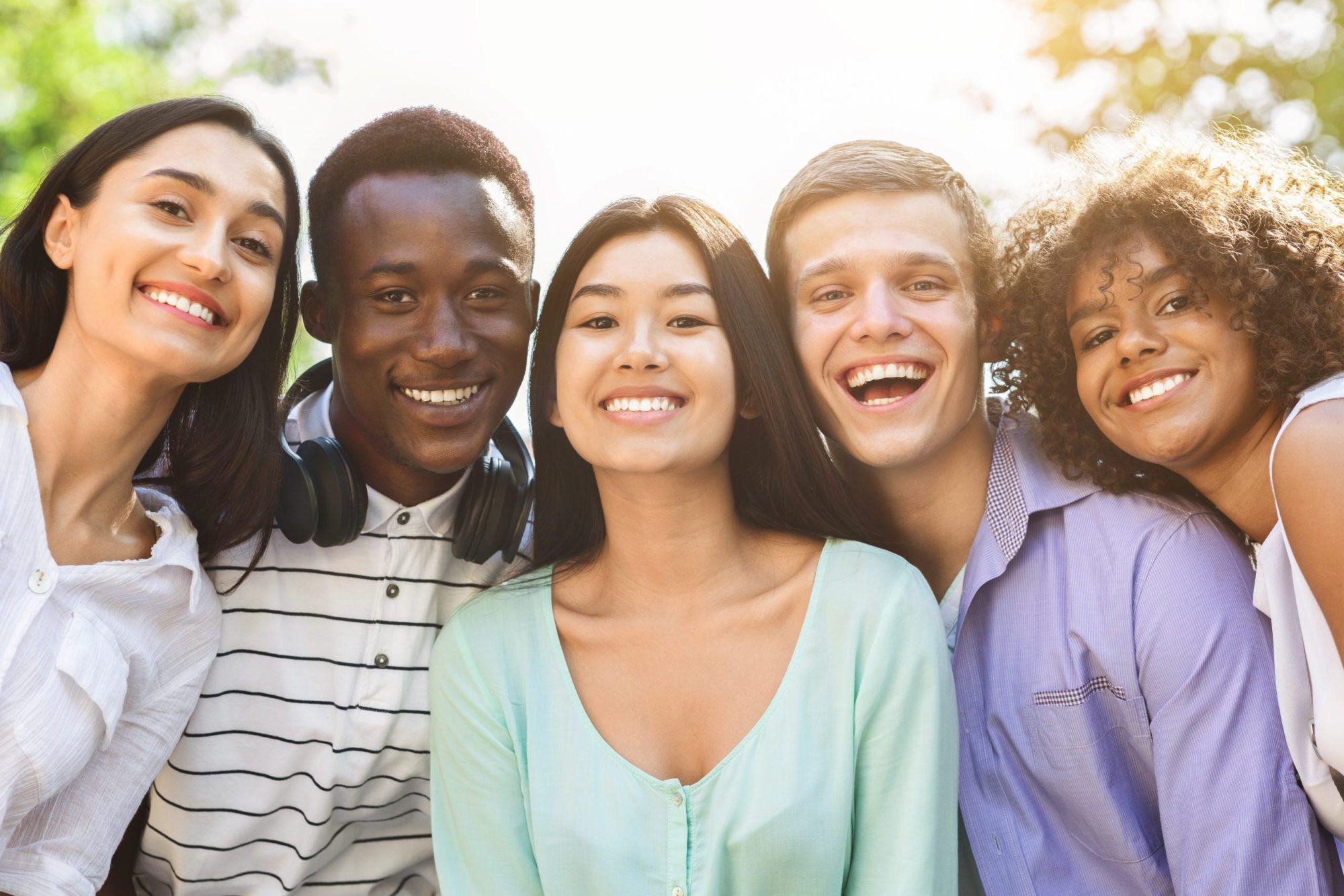 Group of smiling teenage friends posing together outdoors after visiting Ray + Swenson Orthodontics, an orthodontist in Cedar Rapids